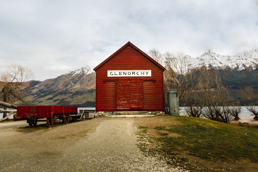 Scenic view of the historic red Glenorchy shed with snowcapped mountains in the background.