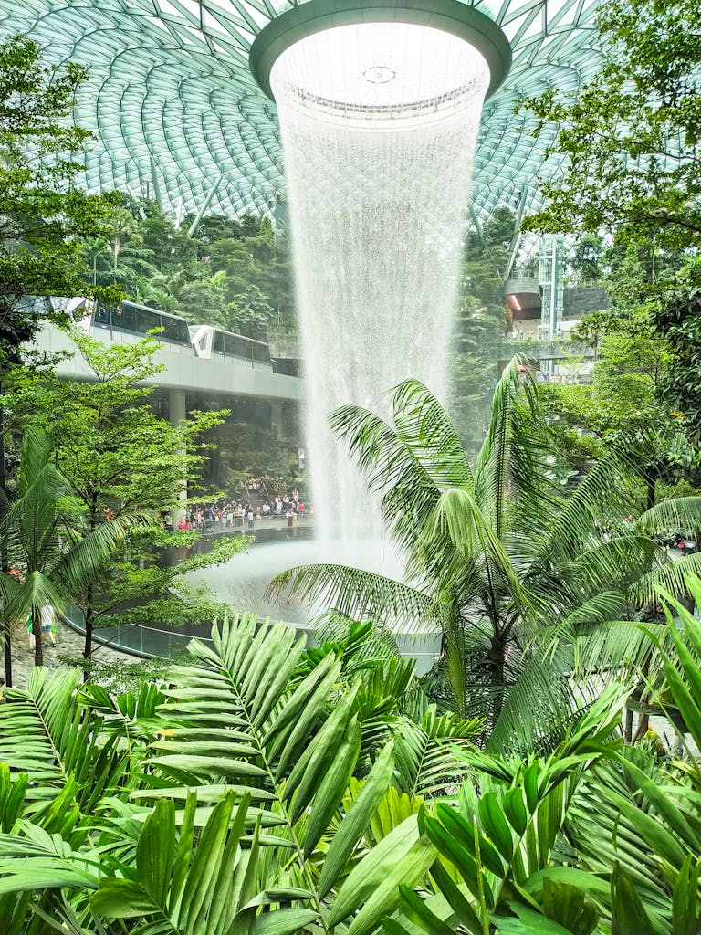 Explore the stunning indoor Rain Vortex waterfall surrounded by lush greenery at Jewel Changi Airport, Singapore.