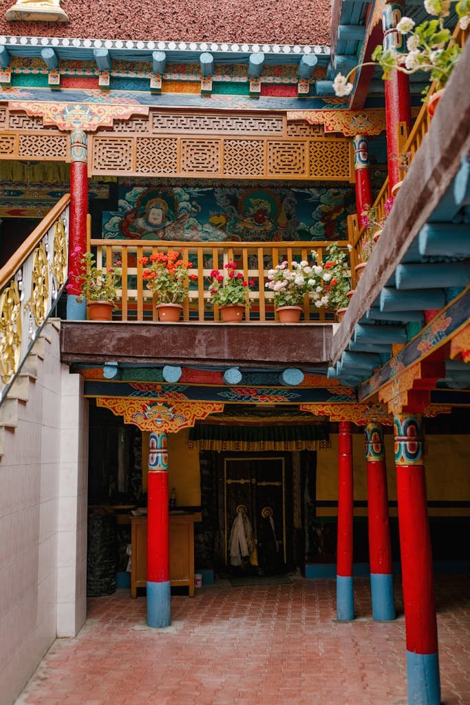 Facade of traditional building located on terrace in street with potted plants near fence and stairway with colorful ornamental columns