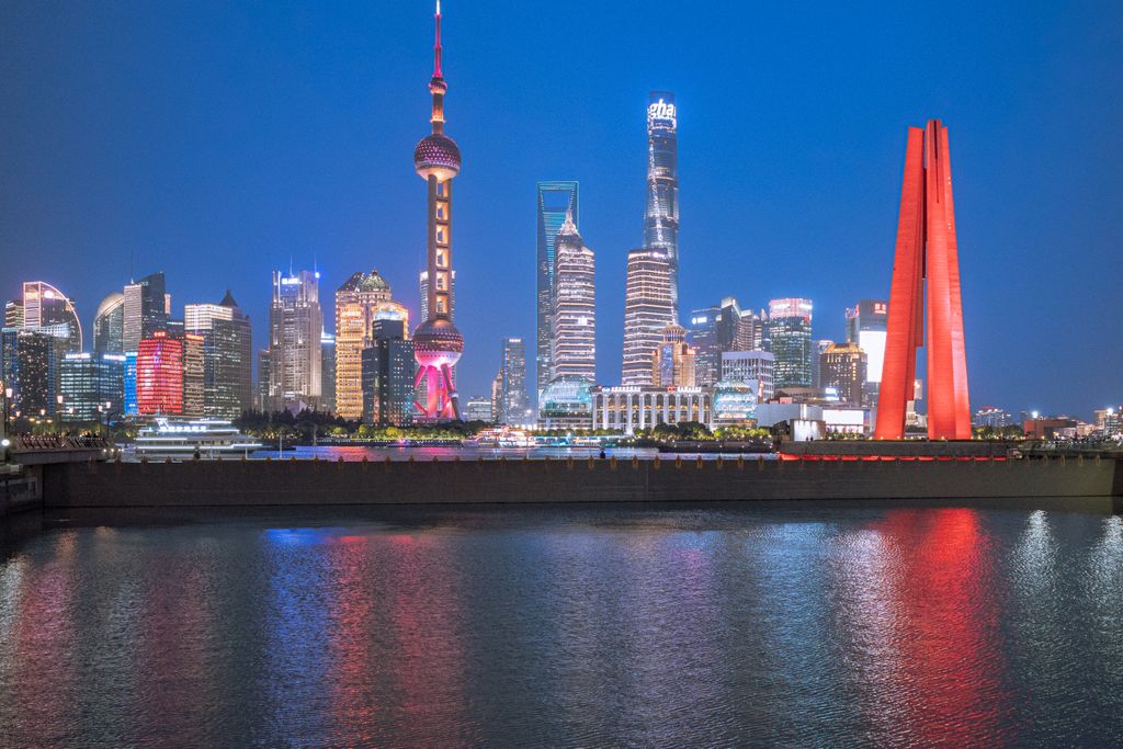 Explore the vibrant Shanghai skyline lit up at night, featuring iconic buildings and reflections on the river.