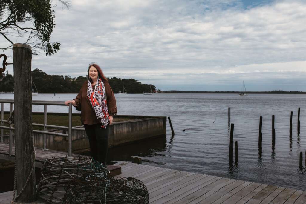 Jacinta Young on a timber jetty overlooking Macquarie Harbour in Strahan, Tasmania